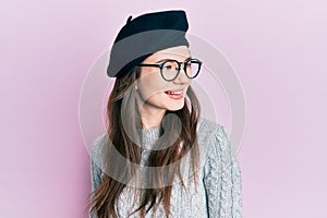 Young beautiful caucasian girl wearing french look with beret looking to side, relax profile pose with natural face and confident