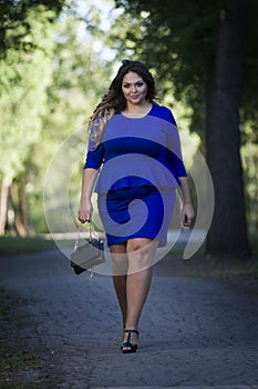 Young beautiful caucasian plus size fashion model in blue dress outdoors, xxl woman on nature