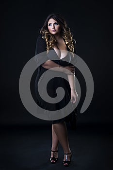 Young beautiful caucasian plus size model in underwear, xxl woman on black background