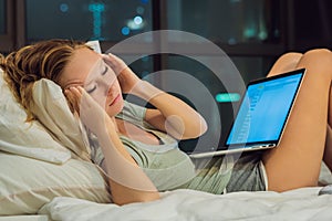 Young beautiful, caucasian, red haired, internet addicted woman working bored, sleepless and tired on her laptop in bed