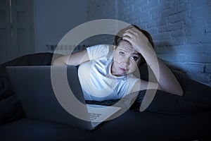 Young beautiful internet addicted sleepless and tired woman working on laptop in bed late at night