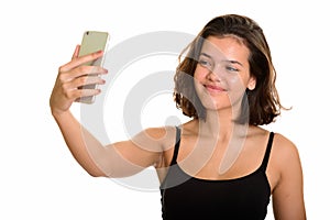 Young beautiful Caucasian teenage girl taking selfie with mobile