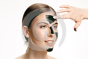 Young beautiful woman applying a mask for the face of the therapeutic black mud. Spa treatment