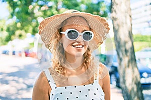 Young beautiful caucasian woman with blond hair smiling happy outdoors on a summer day wearing sunglasses