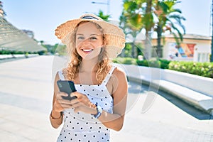 Young beautiful caucasian woman with blond hair smiling happy outdoors using smartphone