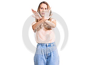 Young beautiful caucasian woman with blond hair wearing casual clothes rejection expression crossing arms doing negative sign,