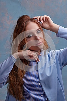 Young beautiful Caucasian woman, in a blue suit,. hands to hair