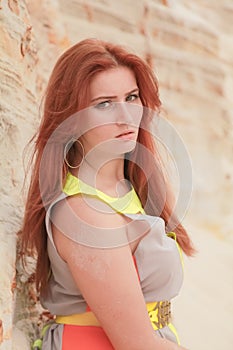 Young beautiful Caucasian woman in colorful long summer chiffon dress posing in desert landscape with sand.
