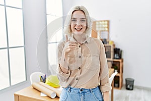 Young beautiful caucasian woman at construction office doing happy thumbs up gesture with hand