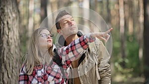 Young beautiful Caucasian woman in eyeglasses pointing talking in slow motion showing man point away. Portrait of