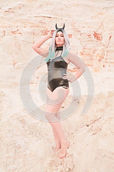 Young beautiful Caucasian woman posing in desert landscape with sand.