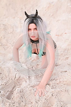 Young beautiful Caucasian woman posing in desert landscape with sand.