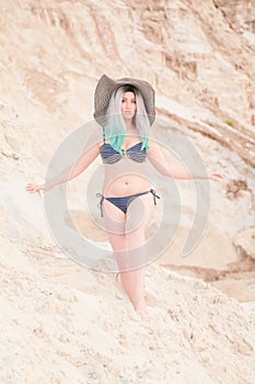 Young beautiful Caucasian woman posing in desert landscape with sand.