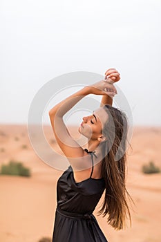Young beautiful Caucasian woman posing in a traditional Emirati dress abaya in Empty Quarter desert landscape