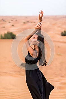 Young beautiful Caucasian woman posing in a traditional Emirati dress abaya in Empty Quarter desert landscape