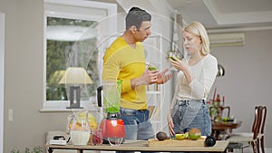 Young beautiful Caucasian woman smelling healthful green drink and making disgust facial expression. Handsome Middle