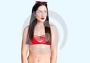 Young beautiful caucasian woman wearing bikini smiling looking to the side and staring away thinking