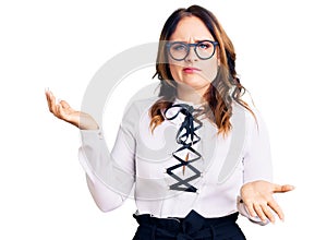 Young beautiful caucasian woman wearing business shirt and glasses clueless and confused expression with arms and hands raised
