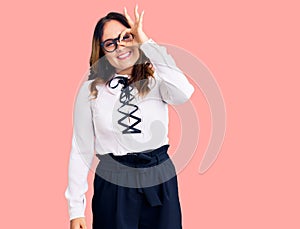 Young beautiful caucasian woman wearing business shirt and glasses smiling happy doing ok sign with hand on eye looking through