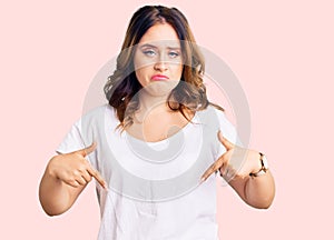 Young beautiful caucasian woman wearing casual white tshirt pointing down looking sad and upset, indicating direction with