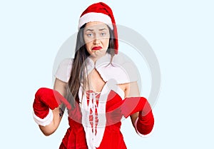 Young beautiful caucasian woman wearing santa claus costume pointing down looking sad and upset, indicating direction with