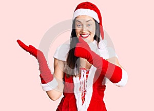 Young beautiful caucasian woman wearing santa claus costume showing palm hand and doing ok gesture with thumbs up, smiling happy