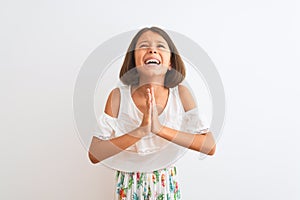 Young beautiful child girl wearing casual dress standing over isolated white background begging and praying with hands together