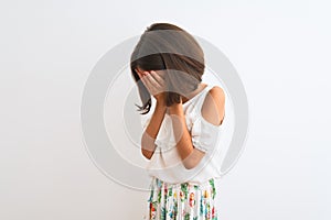 Young beautiful child girl wearing casual dress standing over isolated white background with sad expression covering face with
