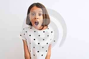 Young beautiful child girl wearing casual t-shirt standing over isolated white background afraid and shocked with surprise