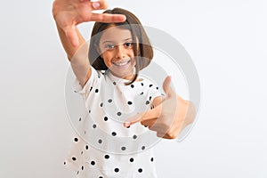 Young beautiful child girl wearing casual t-shirt standing over isolated white background smiling making frame with hands and