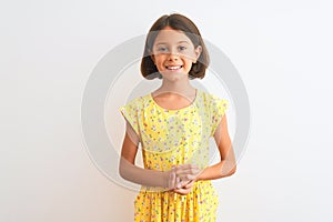 Young beautiful child girl wearing yellow floral dress standing over isolated white background with hands together and crossed