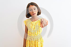 Young beautiful child girl wearing yellow floral dress standing over isolated white background pointing displeased and frustrated