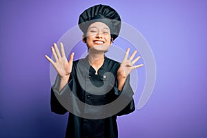 Young beautiful chinese chef woman wearing cooker uniform and hat over purple background showing and pointing up with fingers