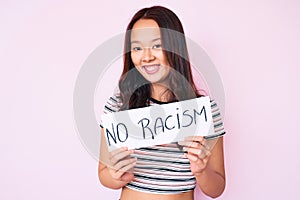 Young beautiful chinese girl holding no racism banner looking positive and happy standing and smiling with a confident smile