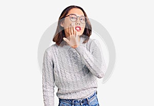 Young beautiful chinese girl wearing casual clothes hand on mouth telling secret rumor, whispering malicious talk conversation