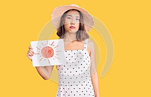 Young beautiful chinese girl wearing summer hat holding sun draw thinking attitude and sober expression looking self confident
