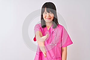 Young beautiful Chinese nurse woman wearing stethoscope over isolated white background smiling friendly offering handshake as