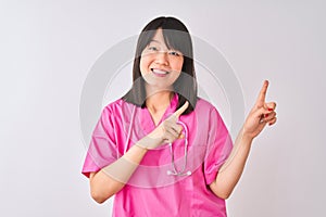 Young beautiful Chinese nurse woman wearing stethoscope over isolated white background smiling and looking at the camera pointing