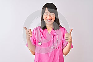 Young beautiful Chinese nurse woman wearing stethoscope over isolated white background success sign doing positive gesture with