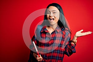 Young beautiful chinese student woman holding book standing over isolated pink background very happy and excited, winner