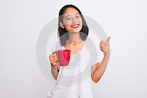 Young beautiful chinese woman drinking cup of coffee over isolated white background happy with big smile doing ok sign, thumb up