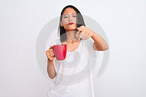 Young beautiful chinese woman drinking cup of coffee over isolated white background pointing with finger to the camera and to you,