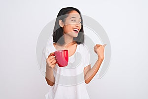 Young beautiful chinese woman drinking cup of coffee over isolated white background pointing and showing with thumb up to the side