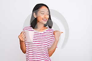 Young beautiful chinese woman drinking cup of coffee over isolated white background pointing and showing with thumb up to the side