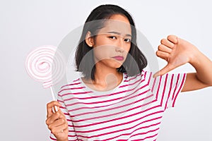Young beautiful chinese woman eating lollipop standing over isolated white background with angry face, negative sign showing