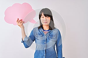 Young beautiful Chinese woman holding cloud speech bubble over isolated white background with a confident expression on smart face