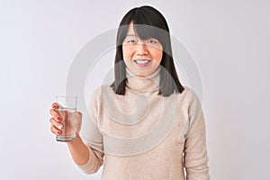 Young beautiful Chinese woman holding glass of water over isolated white background with a happy face standing and smiling with a