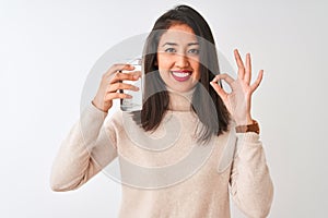 Young beautiful chinese woman holding glass of water standing over isolated white background doing ok sign with fingers, excellent