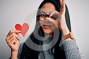 Young beautiful chinese woman holding paper heart over isolated white background with happy face smiling doing ok sign with hand