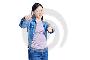 Young beautiful chinese woman pregnant expecting baby approving doing positive gesture with hand, thumbs up smiling and happy for